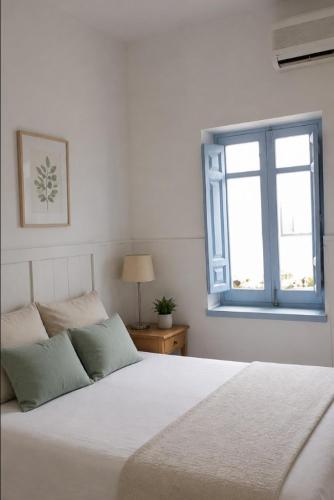 a bedroom with a white bed and a window at Casa granada in Atarfe
