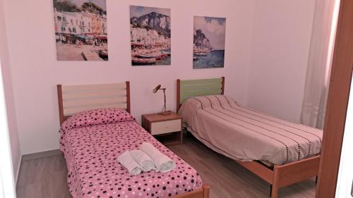 two beds in a room with pictures on the wall at La casa rossa in Siderno Marina