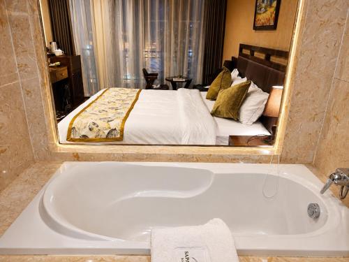 a bathroom with a bath tub with a bed in a mirror at Canvas Sapa Legend Hotel in Sapa