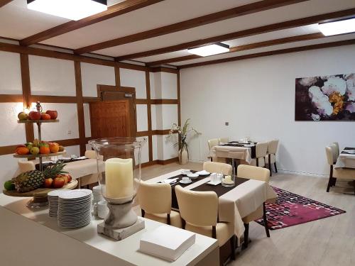 une salle à manger avec des tables et des chaises blanches et une table avec des bougies dans l'établissement Pension Haus Heitzig, à Lippstadt