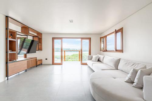 a living room with a white couch and a tv at River & Ocean View House with Pool in Igarassu