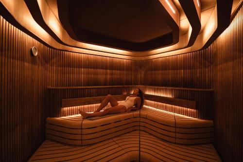 a woman laying on a bed in a sauna at Hotel Les Haras By Stay Collection in Strasbourg