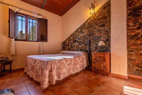 a bedroom with a bed and a stone wall at Casa rural rio yeguas in Azuel