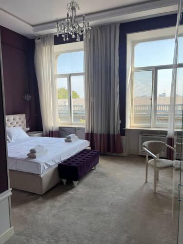 a bedroom with a bed and a chandelier and two windows at Monro in Odesa