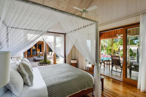 a bedroom with a white canopy bed and a patio at COMO Parrot Cay in Sandy Point