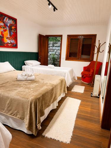 a bedroom with two beds and a red chair at Casa Garten by Concavus in Campos do Jordão