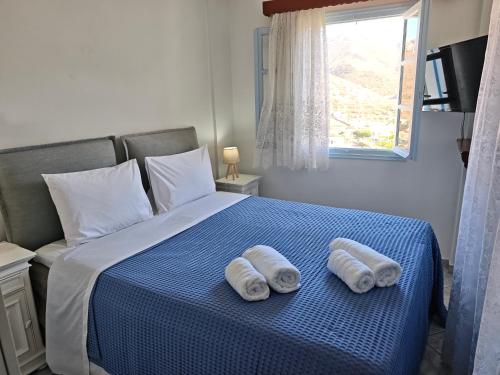 two towels are sitting on a blue bed with a window at Ageon Amorgos in Amorgos