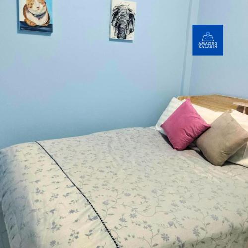 a bed in a room with two pictures on the wall at Aura Home Kalasin in Kalasin