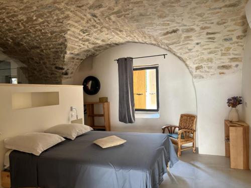 a bedroom with a bed and a stone wall at Maison éla in Bessas