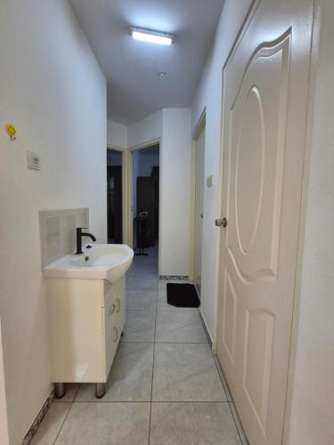 a bathroom with a sink and a white door at Sterappel Sun Stay in Paramaribo