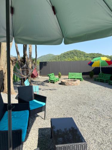 a patio with chairs and an umbrella and benches at Hillside Shilda in Shilda
