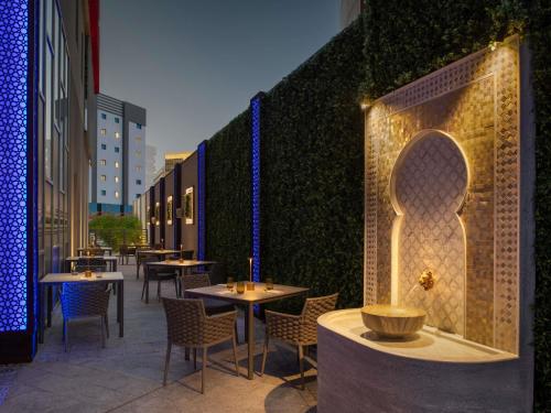 a restaurant with tables and chairs and a green wall at ibis Doha in Doha