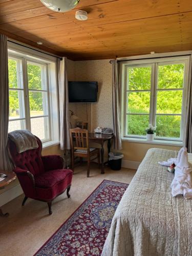 a bedroom with a bed and a chair and windows at Wanbo Herrgård in Nedre Vanbo