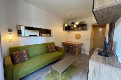a living room with a green couch and a table at Appart T2 pers Risoul Proche pistes in Risoul