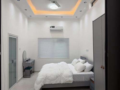 a white bedroom with a bed and a window at Nana's Villa in Danfa
