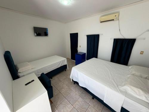 a hotel room with two beds and a tv at Pousada Shopping do Sono in Jaciara