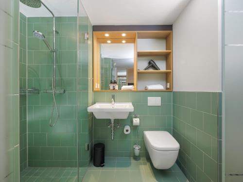 a green bathroom with a sink and a shower at smartments München Parkstadt Schwabing in Munich