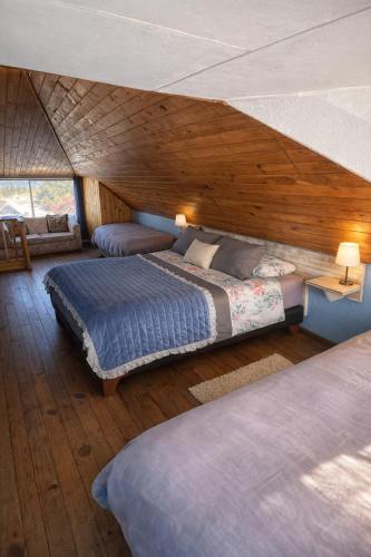a bedroom with two beds and a wooden ceiling at Hostal Boutique F in El Quisco