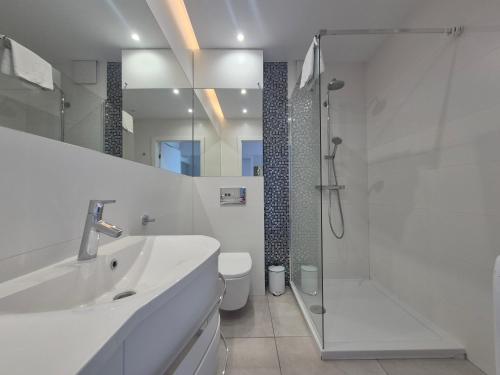 a white bathroom with a shower and a sink at Apartamenty I.M.A Towarowa in Poznań
