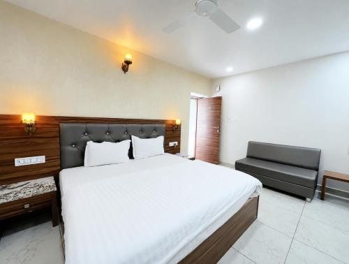 a bedroom with a large white bed and a chair at Hotel Aradhana In Mount Abu in Mount Ābu