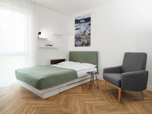 a bedroom with a bed and a chair at smartments München Parkstadt Schwabing in Munich