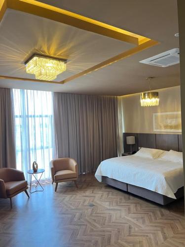 a bedroom with a large bed and two chairs at Jacques Georges Tower in Pelotas