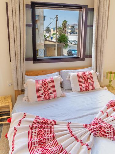 two beds in a room with a window at TAMOUNT Surf House in Agadir