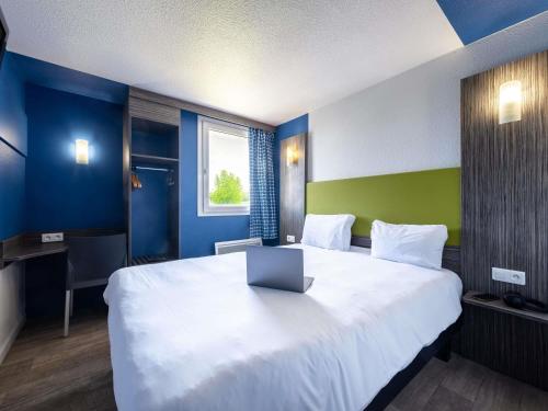 a hotel room with a large bed with a laptop on it at greet Chartres Est in Chartres