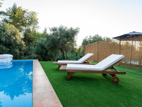 a lawn with two lounge chairs and a pool at Green Olive Luxury Villas in Paliouri