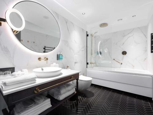 a bathroom with a sink and a tub and a mirror at Movenpick Hotel Tallinn in Tallinn