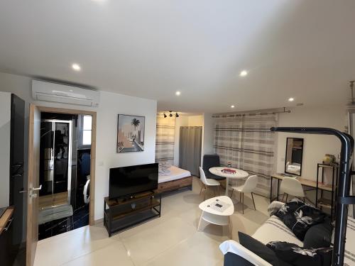 a living room with a couch and a tv and a table at Studio 2 proche centre avec parking in Fréjus