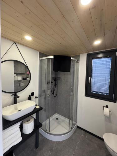 a bathroom with a shower and a sink and a mirror at Domek nad plażą in Chańcza