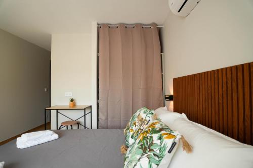 a bedroom with a bed with a curtain and a table at Studio M Les Suites Du Roubion in Montélimar