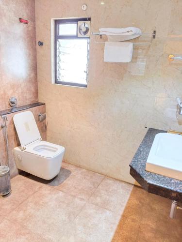 a bathroom with a toilet and a sink at NAKSHATRA Hotel, Restaurant & Banquet in Barddhamān