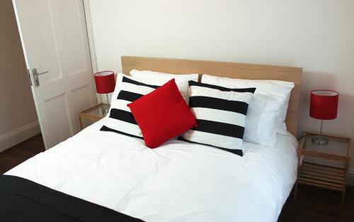 a bed with black and white pillows and a red pillow at West Hill Apartment in Brighton & Hove