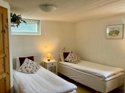 two beds in a small room with a window at Villa María - Charming 40 m2 lower level suite with private entrance in Simrishamn