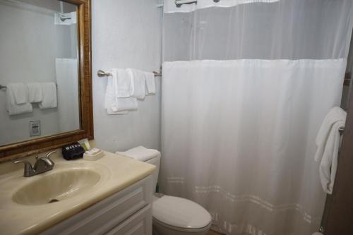 a bathroom with a sink and a toilet and a mirror at Point Pleasant Resort® 1BR Suite with Ocean Views in Nazareth