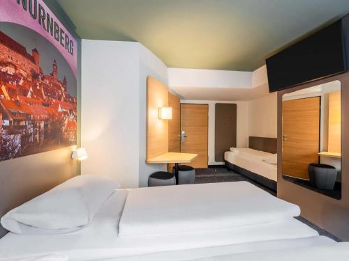 a hotel room with two beds and a tv at B&B Hotel Nürnberg-City in Nuremberg