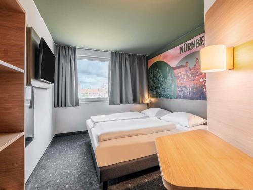 a hotel room with two beds and a tv at B&B Hotel Nürnberg-City in Nuremberg