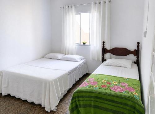 two beds in a room with white walls and a window at Casa na praia bem localizada in Marataizes