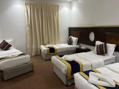 a hotel room with three beds in a room at فندق ربا الحجاز توصيل للحرم in Az Zahrāʼ