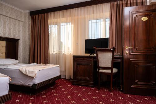 a bedroom with two beds and a desk and a chair at Pensiunea ORIENT in Brăila