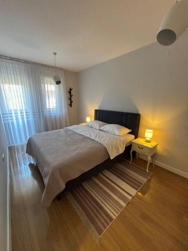 a bedroom with a large bed with two lamps on it at Apartman Vila&Vera in Sremska Mitrovica