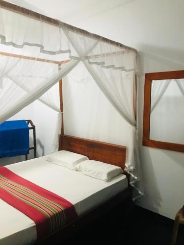 a bedroom with a bed with a canopy and a window at Villa Akeinya in Matara