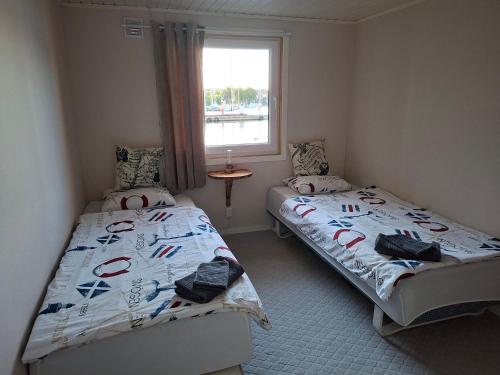 zwei Einzelbetten in einem Zimmer mit Fenster in der Unterkunft Green husbåt in Södertälje