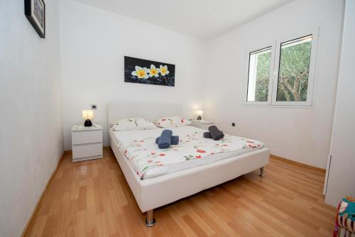 a white bedroom with a large white bed and a window at Villa Best Relax in Okrug Donji