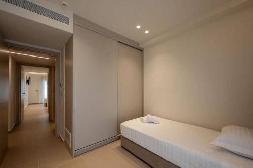 a bedroom with a white bed and a hallway at ΛΑΚΩΝΙΖΕΙΝ Luxury Suites in Sparta