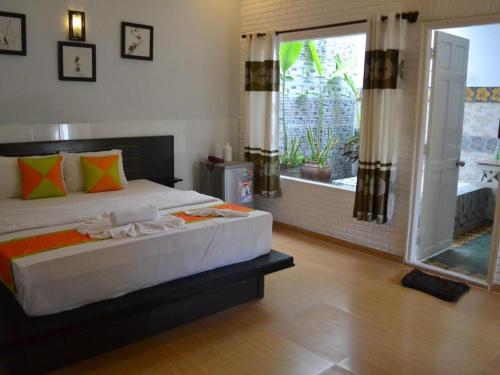 Green Hill Resort and Spa في موي ني: غرفة نوم بسرير كبير ونافذة كبيرة