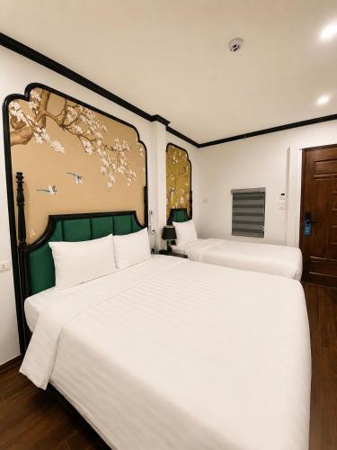 two beds in a room with white sheets at Hanoi Silk Crown Boutique Hotel & Spa in Hanoi