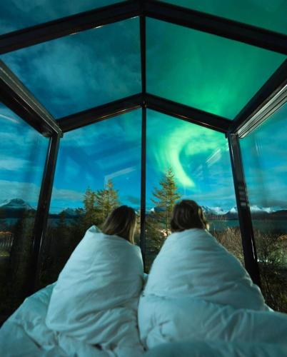 two people laying in bed looking at the northern lights at WonderInn Arctic in Utstrand